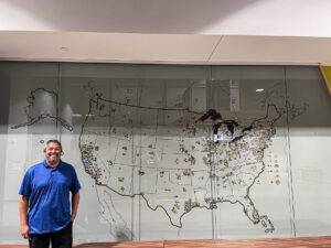 Trevor Ogilvie stands proud next to a map of every United Association of Plumbers and Gasfitters local in the United States. 